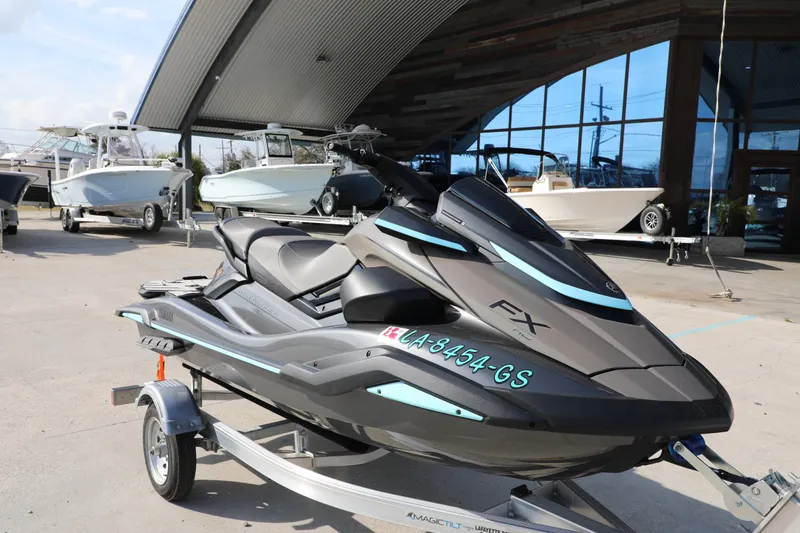 Slide: The Image of 2025 Yamaha WaveRunner FX HO jet ski on trailer, parked near boats. - 11