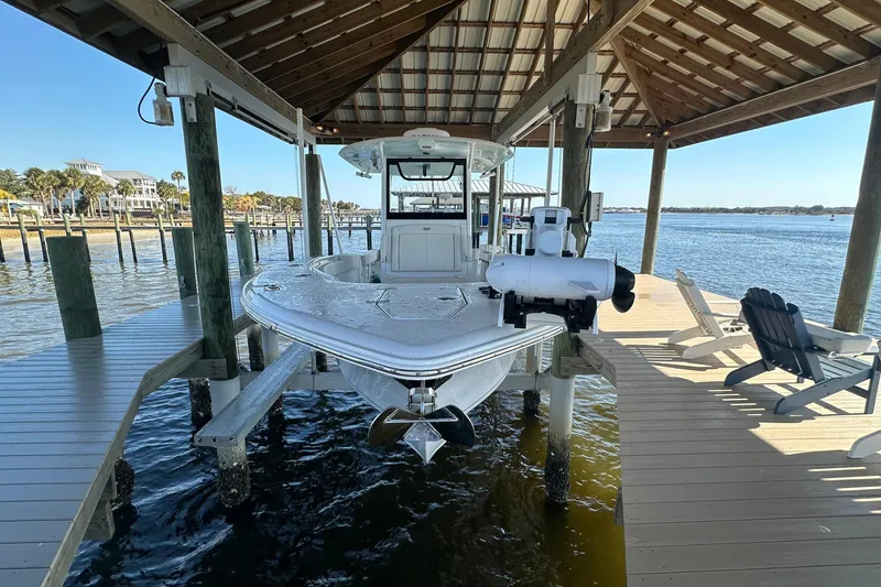 Slide: The Image of 2024 Sea Hunt Gamefish 30 Forward Seating boat docked under a wooden shelter. - 1
