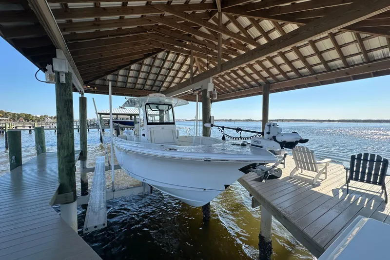 Slide: The Image of 2024 Sea Hunt Gamefish 30 boat docked under a wooden canopy by the water. - 2
