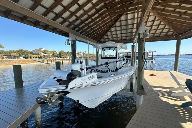 Slide: The Image of 2024 Sea Hunt Gamefish 30 Forward Seating boat docked under a wooden canopy. - 3