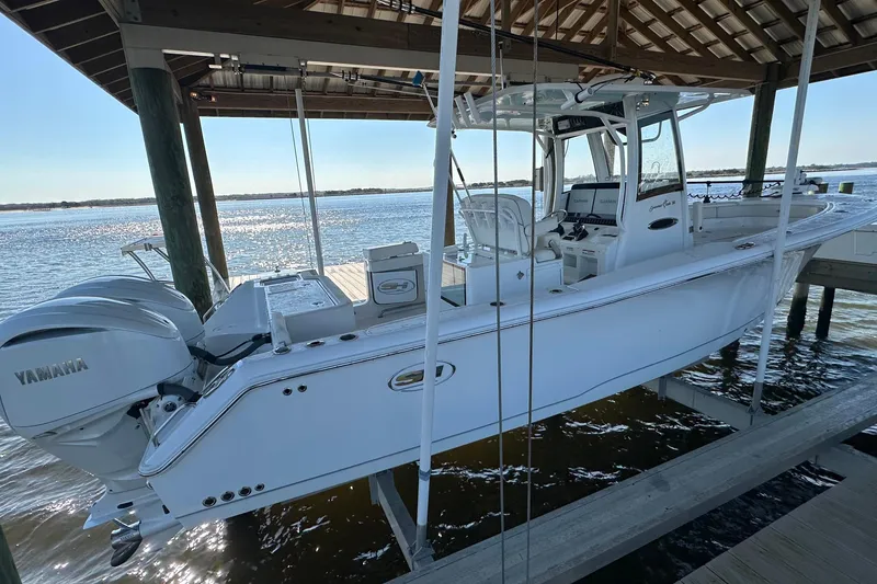 Slide: The Image of 2024 Sea Hunt Gamefish 30 Forward Seating boat docked under a wooden shelter. - 4