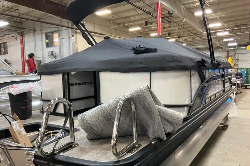 Slide: The Image of 2026 Bennington 22 SSRSE pontoon boat in a warehouse, covered with a black canopy. - 19