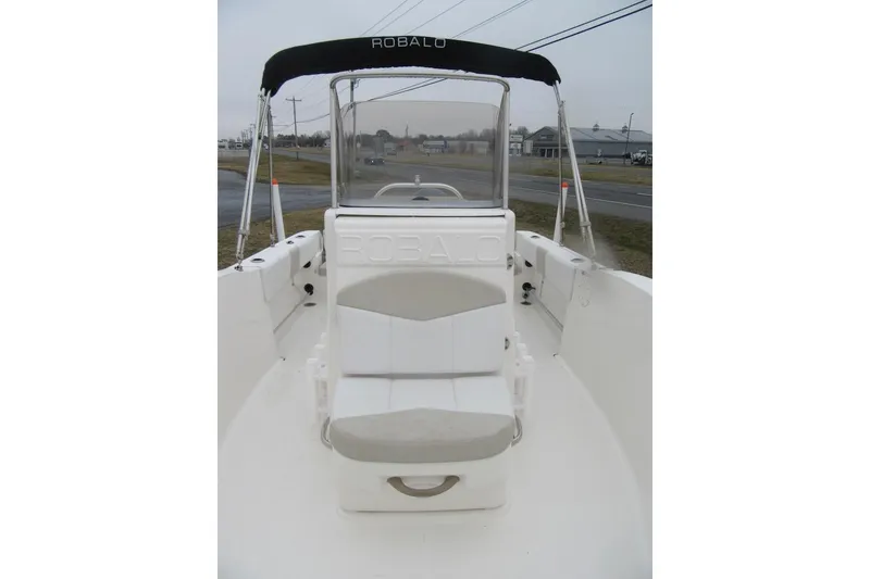 Slide: The Image of 2015 Robalo R180 Center Console boat with seating and canopy, parked near a road. - 12