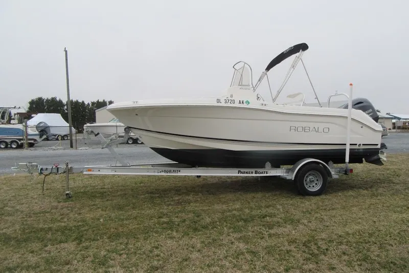 Slide: The Image of 2015 Robalo R180 Center Console boat on trailer, parked on grass. - 5