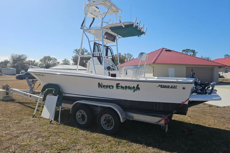 Slide: The Image of 1996 Mako 231 Center Console boat on trailer, labeled "Never Enough," parked outdoors. - 11