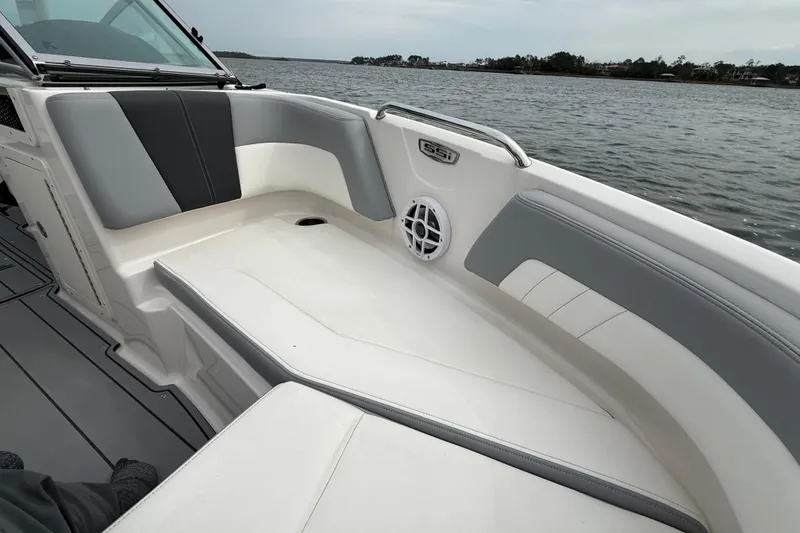 Slide: The Image of 2024 Chaparral 21 SSi OB boat interior with gray and white seating, on calm water. - 21