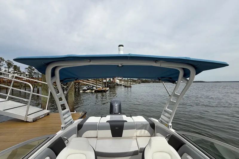 Slide: The Image of 2024 Chaparral 21 SSi OB boat with blue canopy docked by the water. - 26