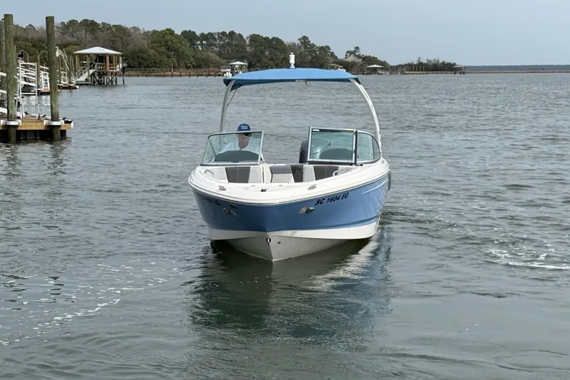 Slide: The Image of 2024 Chaparral 21 SSi OB boat cruising on a calm lake near a dock. - 4
