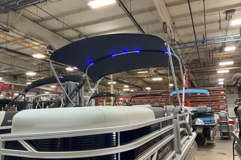 Slide: The Image of 2026 Bennington 22 SSRSF pontoon boat with blue LED canopy lights in a factory setting. - 18