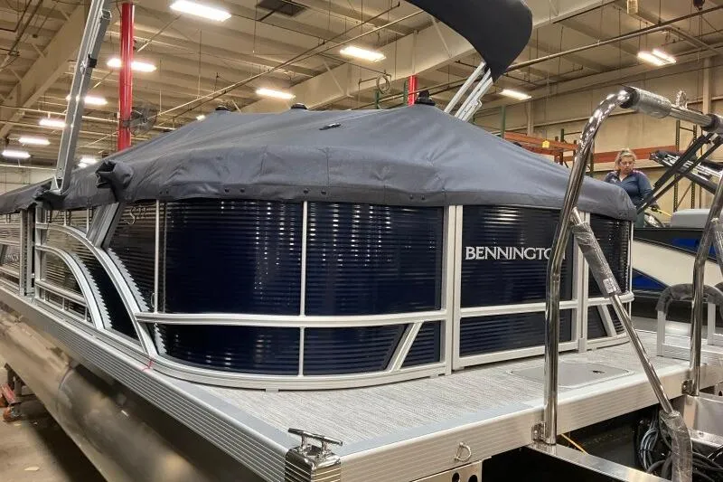 Slide: The Image of 2026 Bennington 22 SSRSF pontoon boat in a showroom, covered and ready for display. - 22