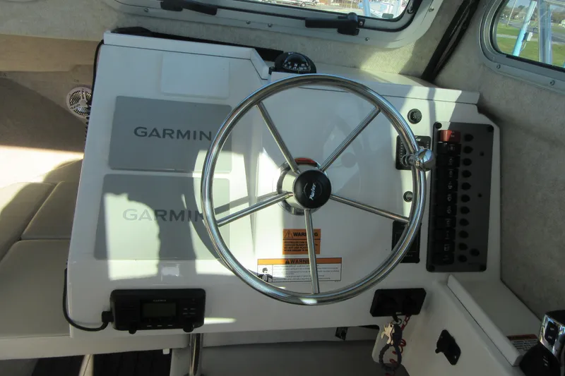 Slide: The Image of 2024 Parker 2320 SL Sport Cabin helm with Garmin navigation and steering wheel. - 26