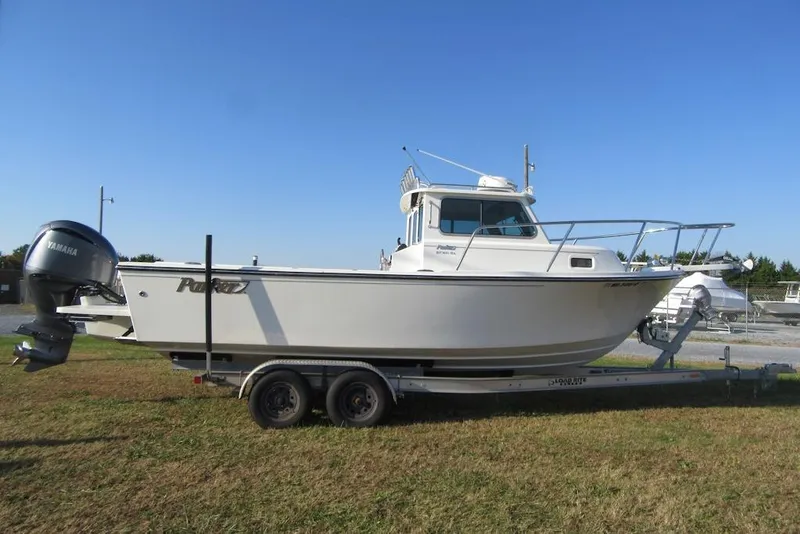Slide: The Image of 2024 Parker 2320 SL Sport Cabin boat on trailer, side view, clear sky background. - 5