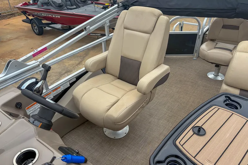 Slide: The Image of 2022 Sun Tracker Fishin' Barge 22 DLX interior with beige captain's chair and steering wheel. - 11