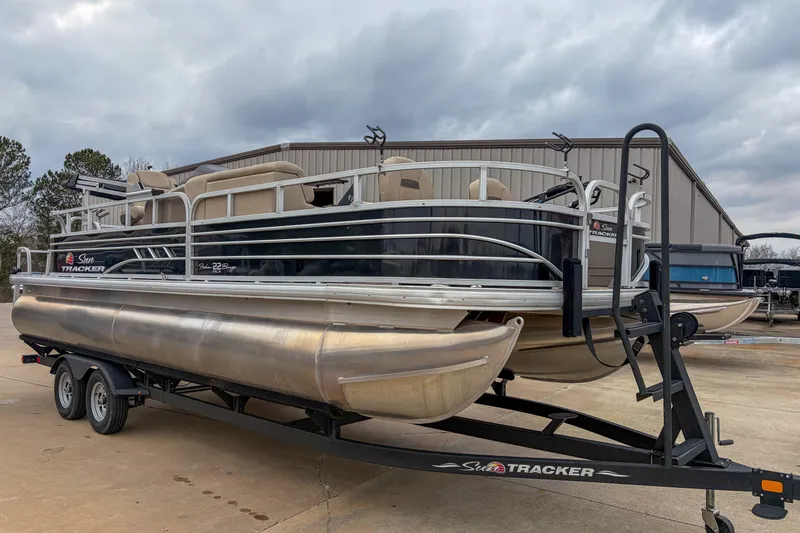 Slide: The Image of 2022 Sun Tracker Fishin' Barge 22 DLX pontoon boat on trailer, parked outdoors. - 3