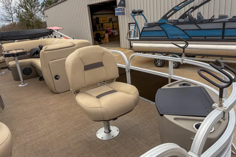 Slide: The Image of 2022 Sun Tracker Fishin' Barge 22 DLX interior with beige seating and fishing rod holders. - 7