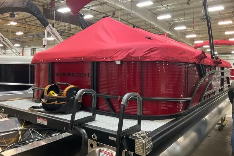 Slide: The Image of 2026 Bennington 22 SSRSF pontoon boat with red cover in a showroom. - 21