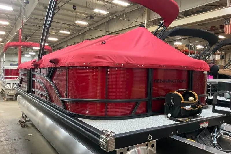 Slide: The Image of 2026 Bennington 22 SSRSF pontoon boat with red cover in a warehouse setting. - 22