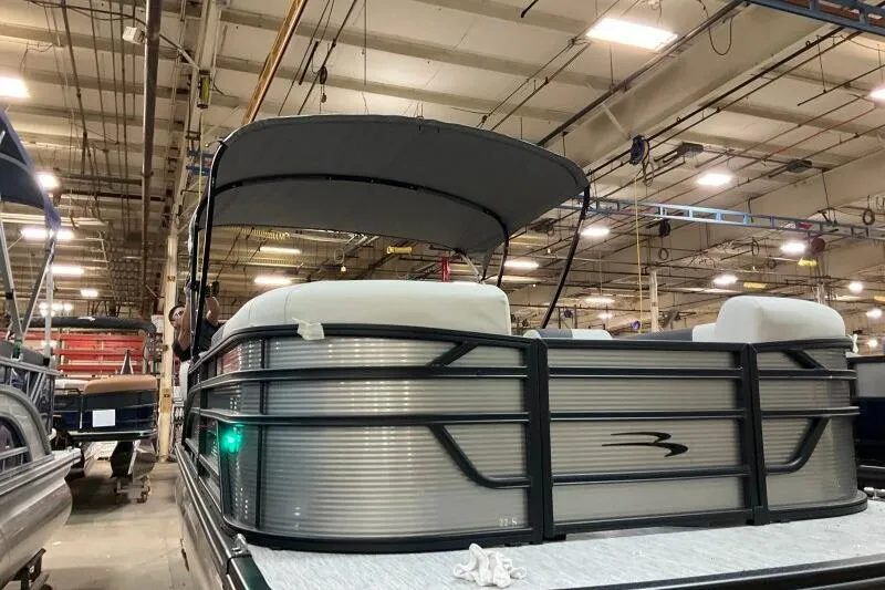Slide: The Image of 2026 Bennington 22 SSRSF pontoon boat in a factory setting, under bright lights. - 17