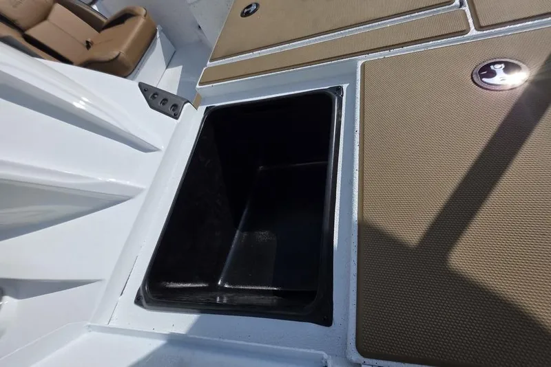 Slide: The Image of 2026 Xpress H18 boat storage compartment with brown cushioned seating. - 17