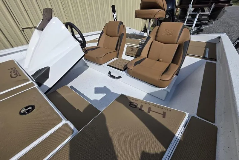 Slide: The Image of 2026 Xpress H18 boat interior with brown seats and steering console. - 21