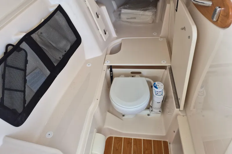 Slide: The Image of 2026 Grady-White Freedom 307 boat interior with compact marine toilet and storage. - 24
