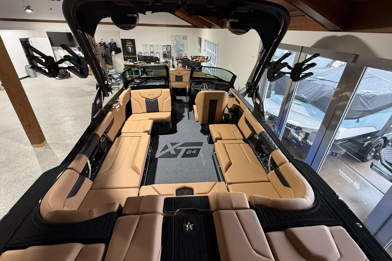Slide: The Image of 2026 MasterCraft XT24 boat interior with tan seating and modern design in showroom. - 5