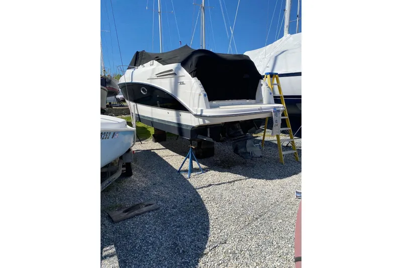 Slide: The Image of 2006 Maxum 2600 SE boat on gravel, covered and elevated, with a ladder nearby. - 29