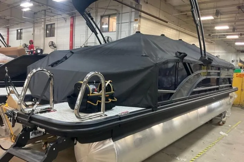 Slide: The Image of 2026 Bennington 23 SSBSF pontoon boat with black cover in a warehouse setting. - 22