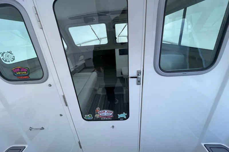 Slide: The Image of 2023 Parker 2120 Sport Cabin interior view through glass door, featuring cabin seating. - 20