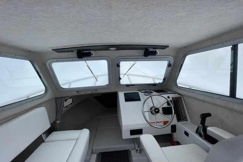 Slide: The Image of Interior of 2023 Parker 2120 Sport Cabin boat with steering wheel and seating. - 25
