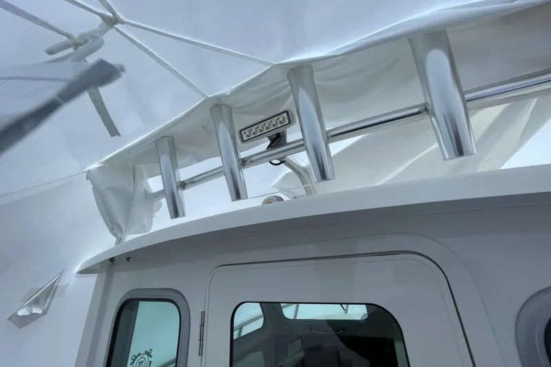 Slide: The Image of 2023 Parker 2120 Sport Cabin boat with rod holders and canopy detail. - 26