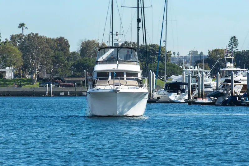 Slide: The Image of 1996 Navigator 5300 Classic yacht cruising in a marina, surrounded by other boats and lush greenery. - 9