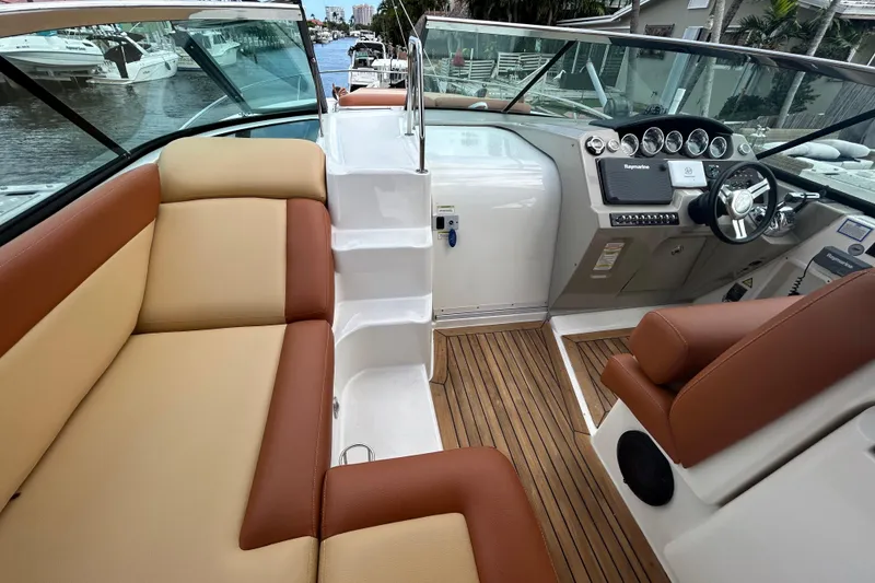 Slide: The Image of 2014 Sea Ray 370 Venture boat interior with tan and brown seating, wooden flooring, and control panel. - 17