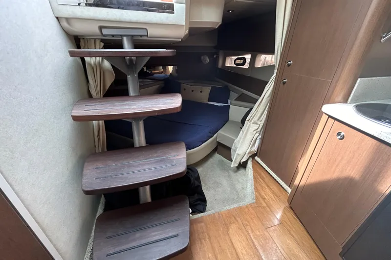 Slide: The Image of 2014 Sea Ray 370 Venture cabin interior with wooden steps and cozy sleeping area. - 25