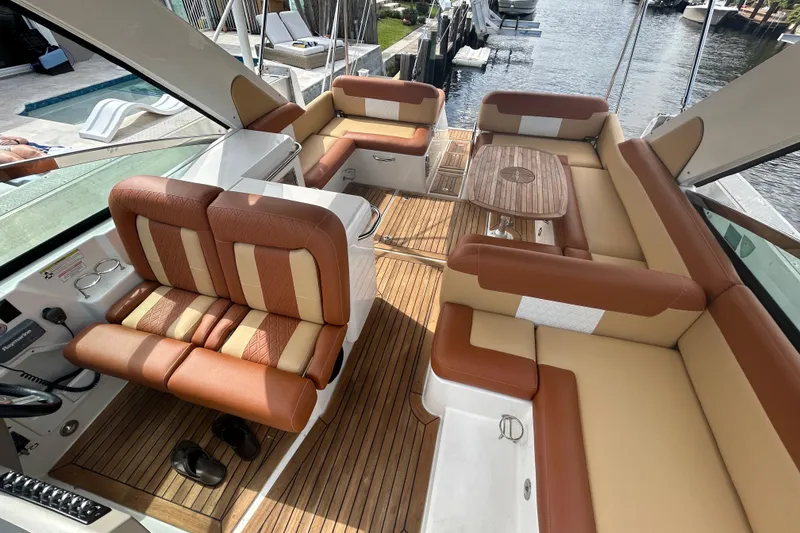 Slide: The Image of 2014 Sea Ray 370 Venture boat interior with tan and brown seating, wooden flooring, and a table. - 40