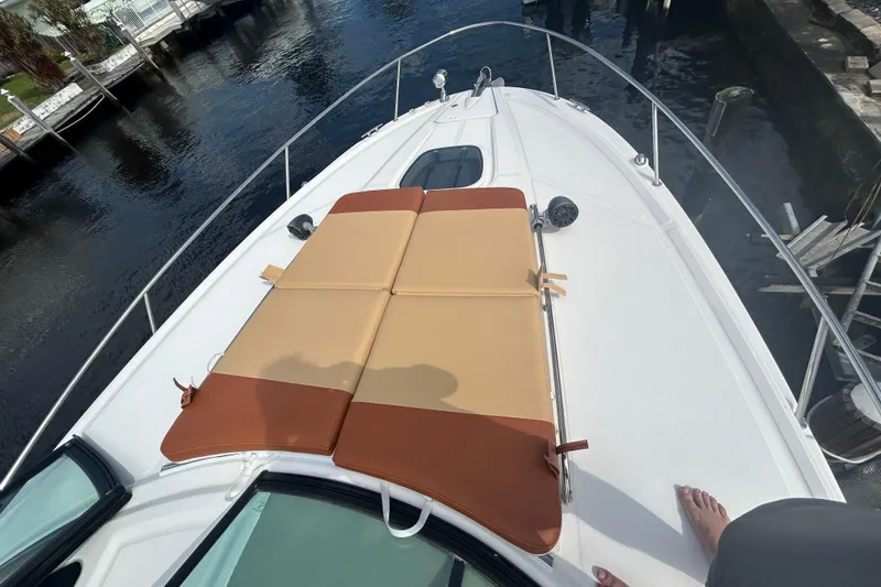 Slide: The Image of 2014 Sea Ray 370 Venture boat with sunpad on deck, docked by water. - 43