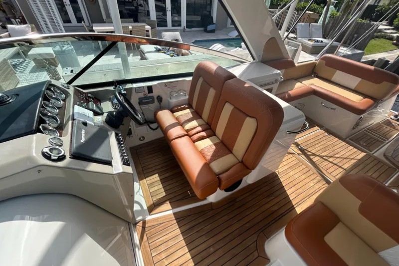 Slide: The Image of 2014 Sea Ray 370 Venture boat interior with tan and brown seating, wooden flooring, and control panel. - 45
