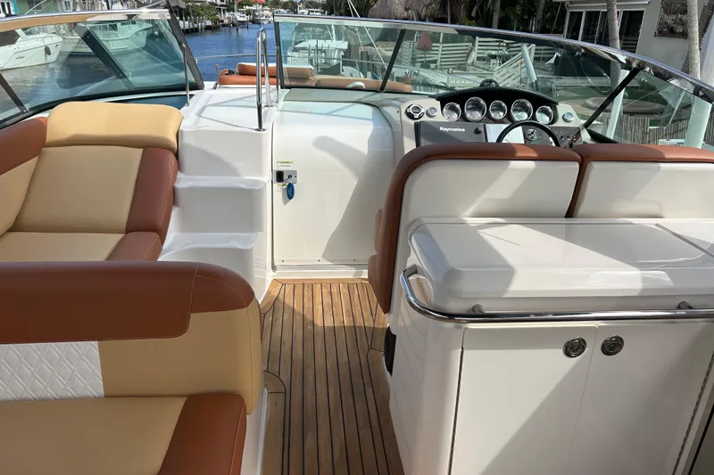 Slide: The Image of 2014 Sea Ray 370 Venture boat interior with tan and brown seating, wooden deck, and control panel. - 47