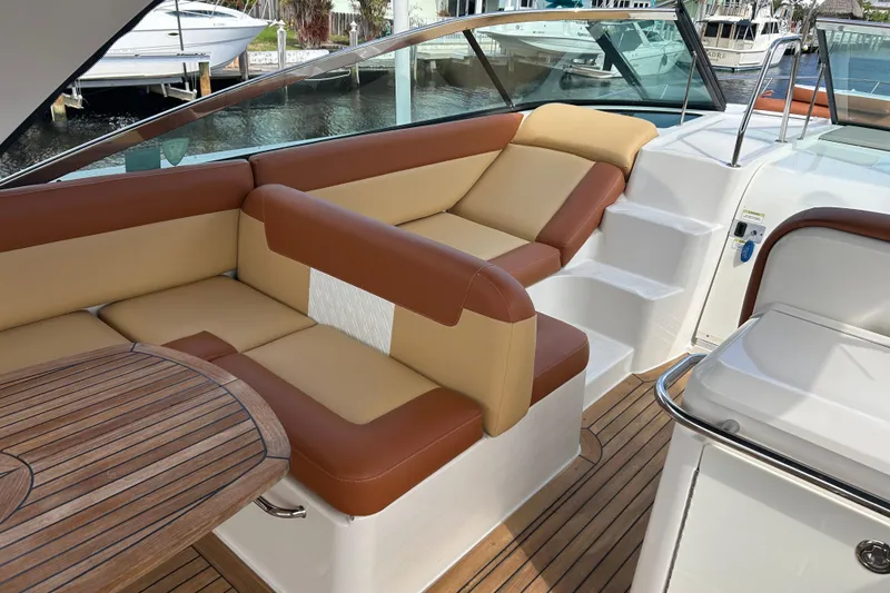Slide: The Image of 2014 Sea Ray 370 Venture boat interior with tan and brown seating, wooden table, and steps. - 48