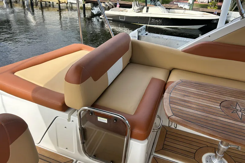 Slide: The Image of 2014 Sea Ray 370 Venture boat interior with tan and brown seating, wooden table, and water view. - 49