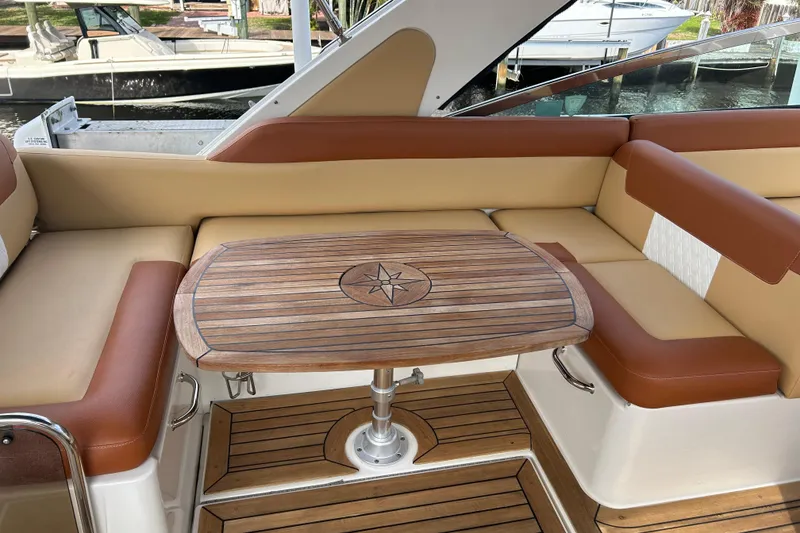 Slide: The Image of Luxurious seating area on a 2014 Sea Ray 370 Venture with wooden table and leather cushions. - 50