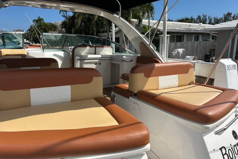 Slide: The Image of 2014 Sea Ray 370 Venture boat interior with tan and brown seating, docked outdoors. - 52
