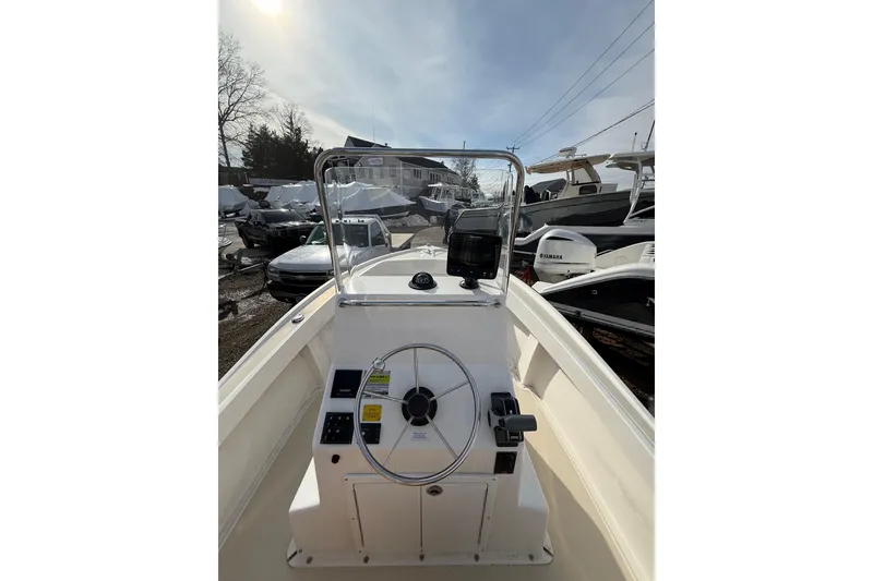 Slide: The Image of 2018 NorthCoast 190 Center Console boat with steering wheel and controls, docked outdoors. - 4