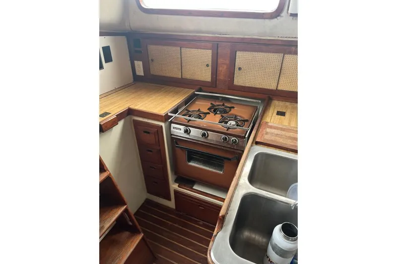 Slide: The Image of 1979 Downeaster 38 yacht kitchen with stove, sink, and wooden cabinetry. - 10