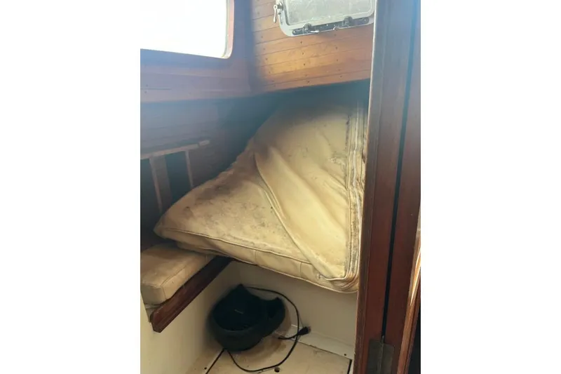 Slide: The Image of 1979 Downeaster 38 cabin interior with a worn mattress and wooden paneling. - 12