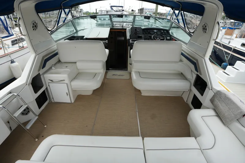 Slide: The Image of Interior of a 1993 Sea Ray 400 Express Cruiser with white seating and blue canopy. - 10