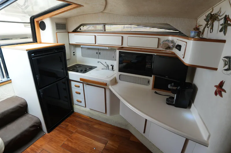 Slide: The Image of 1993 Sea Ray 400 Express Cruiser kitchen with stove, sink, fridge, and microwave. - 16