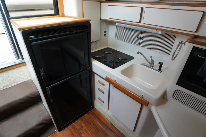Slide: The Image of 1993 Sea Ray 400 Express Cruiser kitchen with stove, sink, and refrigerator. - 17