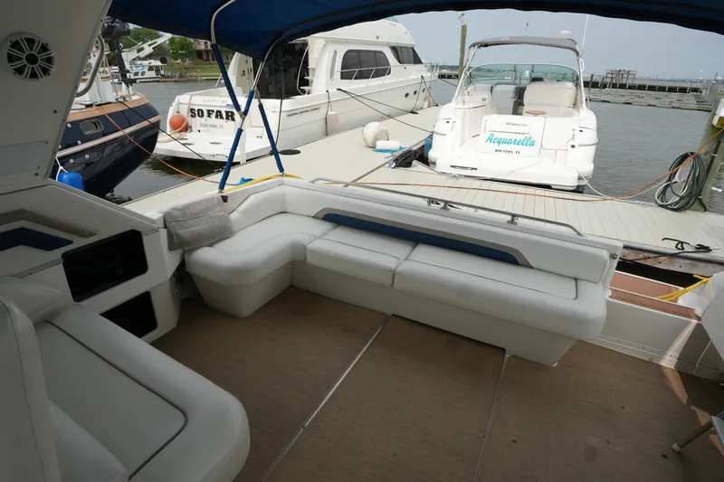 Slide: The Image of 1993 Sea Ray 400 Express Cruiser interior with white seating at a marina dock. - 7