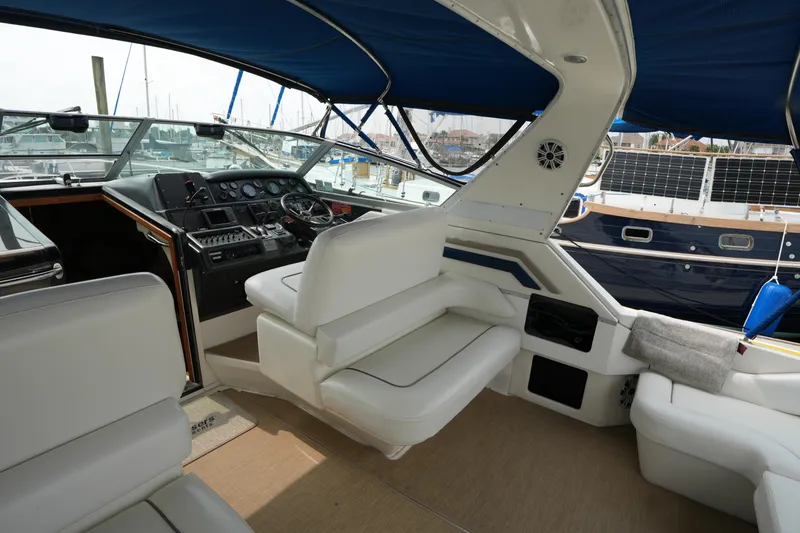 Slide: The Image of 1993 Sea Ray 400 Express Cruiser interior with helm, white seating, and blue canopy. - 8